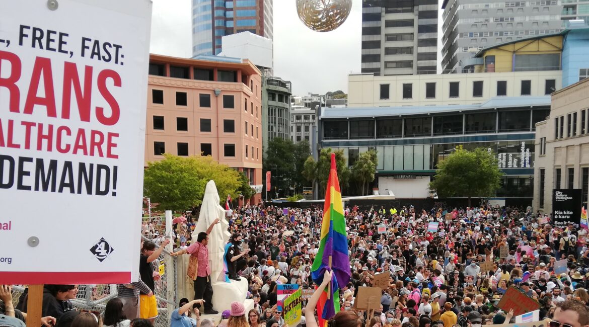 Demonstration with rainbow flag and placard reading: "Full, free, fast: trans healthcare on demand